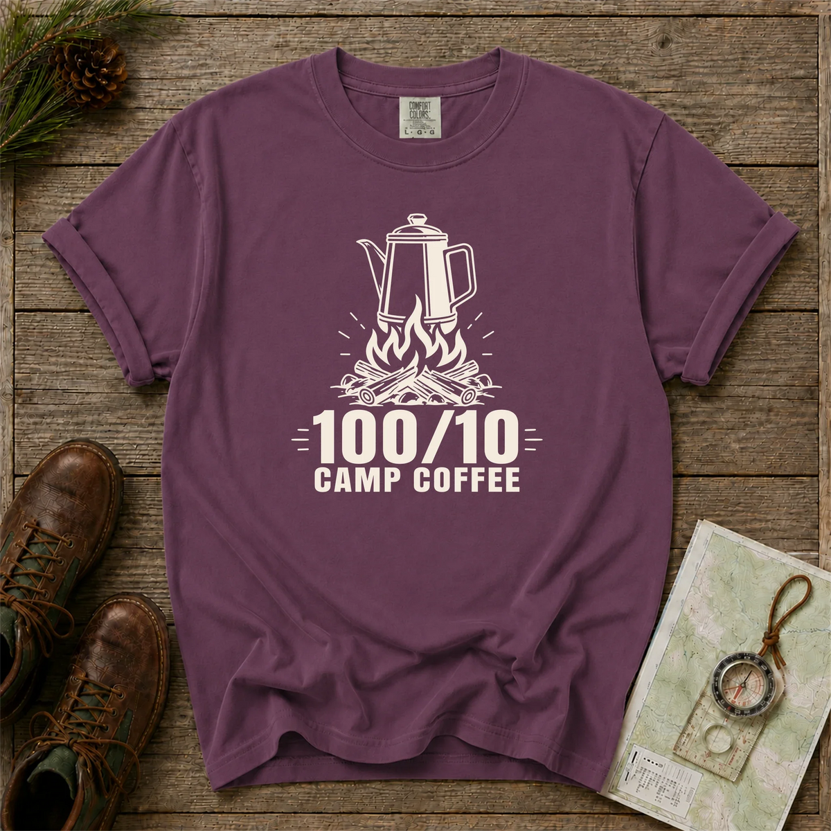 100/10 Camp Coffee tee in Berry on a wooden table